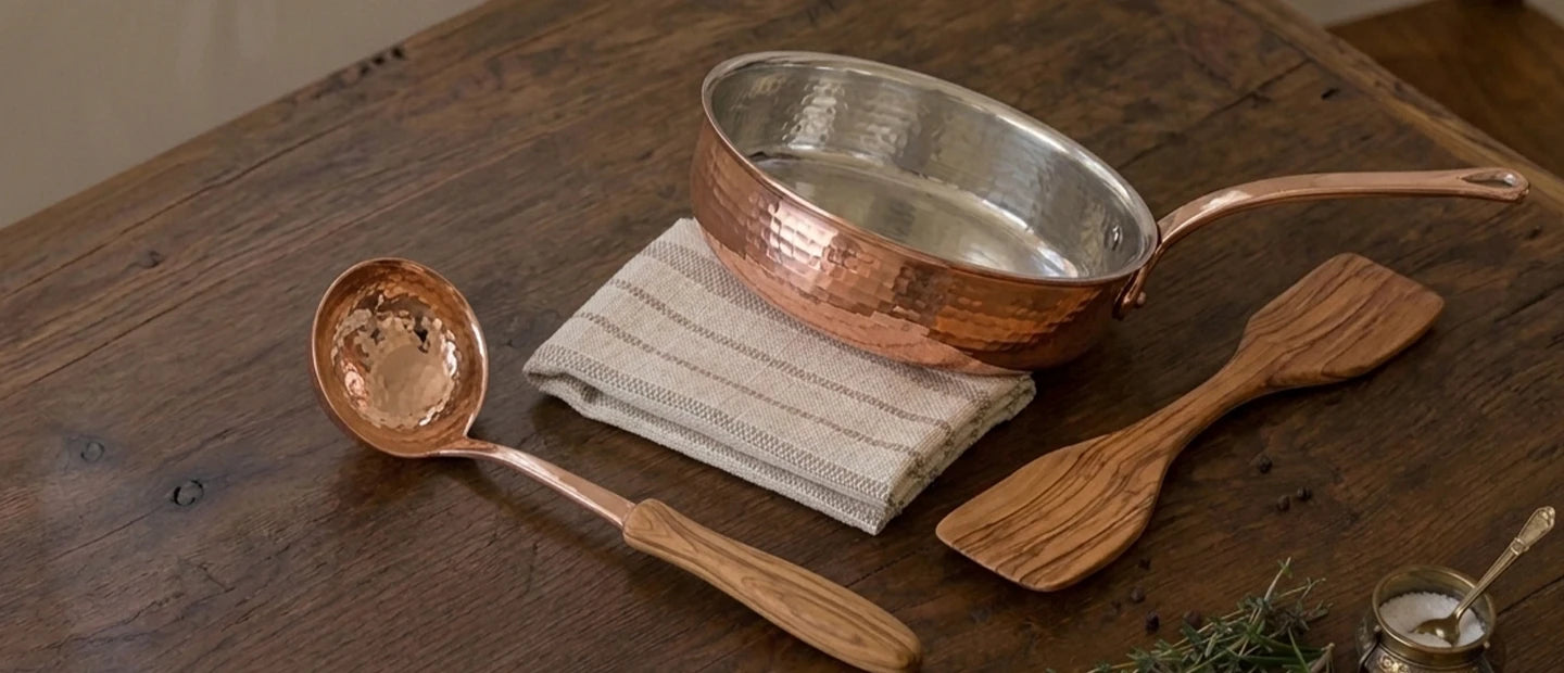 Copper cookware and wooden utensils on a kitchen table